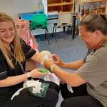 Participant applying an arm bandage to another person as part of first aid training exercises.