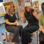Two participants seated and practising applying a bandage to an arm.