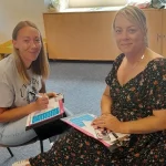 Two participants completing a paired first aid activity using training materials.