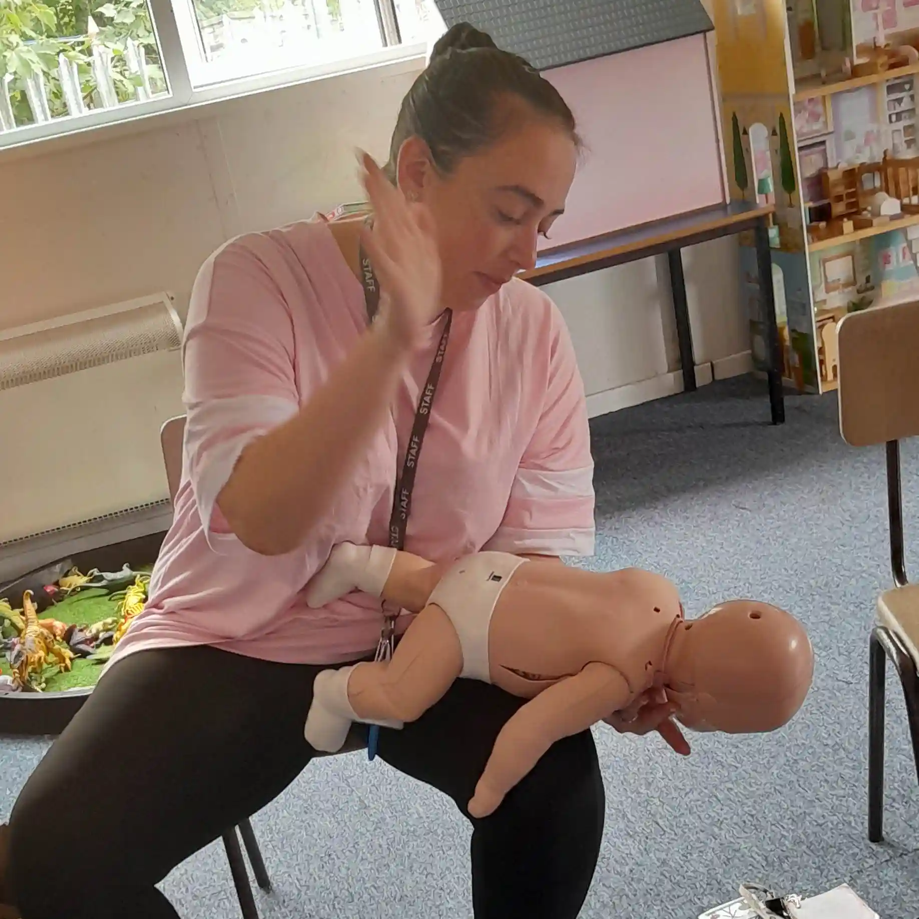 A first aid learner practising the back blow technique for infant choking relief using a specialized baby manikin.