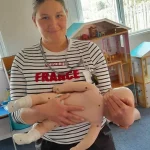 Demonstrating safe infant carrying position in first-aid class.