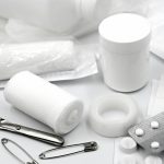 A detailed arrangement of essential first aid supplies including bandages, safety pins, and medication.